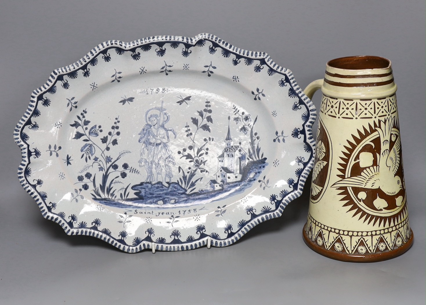 A Brannum sgraffito jug dated 1881 and a French faience serving dish, 42cm
